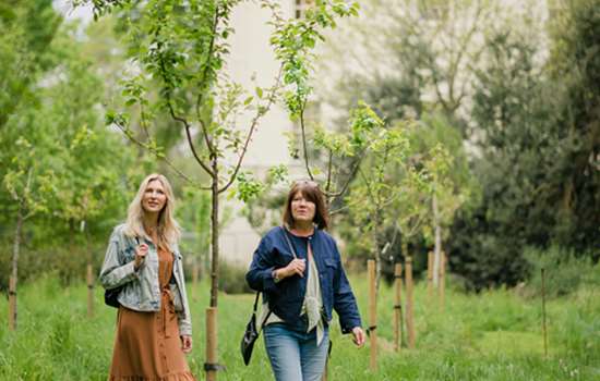 Two women walk through the gardens with view of Marble Hill House in the background.