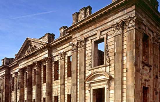 A side view of the ruins of Sutton Scarsdale Hall underneath a blue sky.